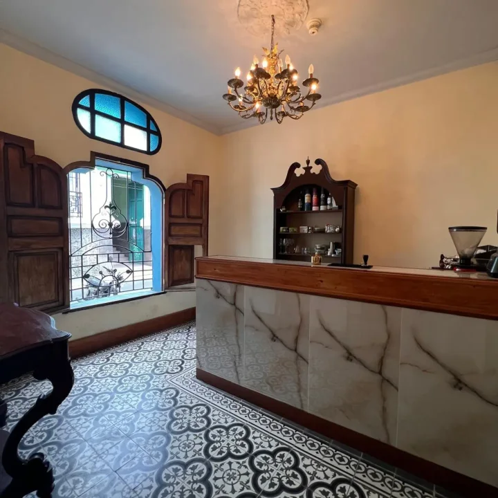 Barra de la posada bajo una lámpara de araña, con ventana de vitral y piso de mosaico