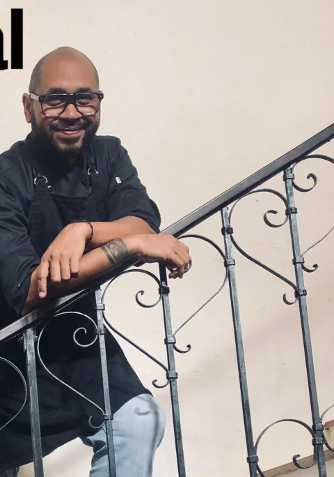 El chef Marcel Nogal, sonriente, apoyado en la baranda de una escalera de la casa