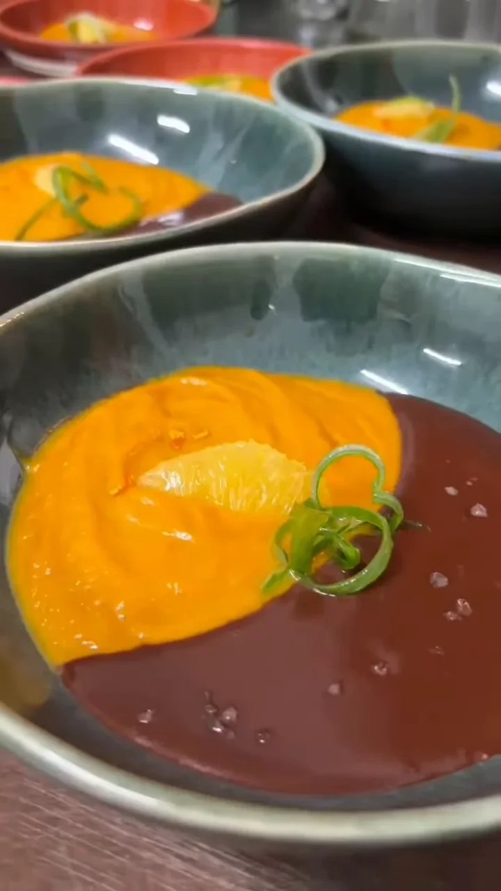 Crema anaranjada con salsa oscura y un toque de cebollín