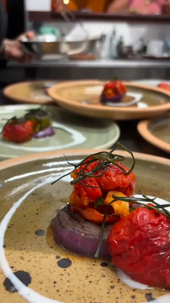 Tomates asados sobre cebolla morada, servidos en plato de cerámica